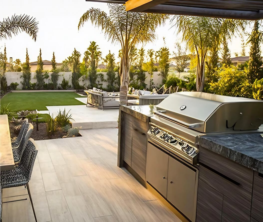 An outdoor kitchen featuring a grill and a dining table, set in a spacious garden environment, ideal for gatherings.