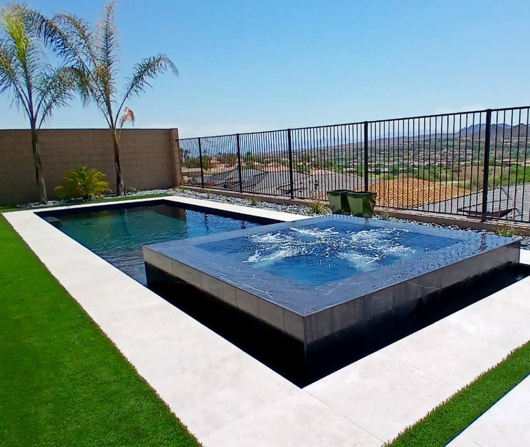 Rectangular pool surrounded by green, clean cut grass.