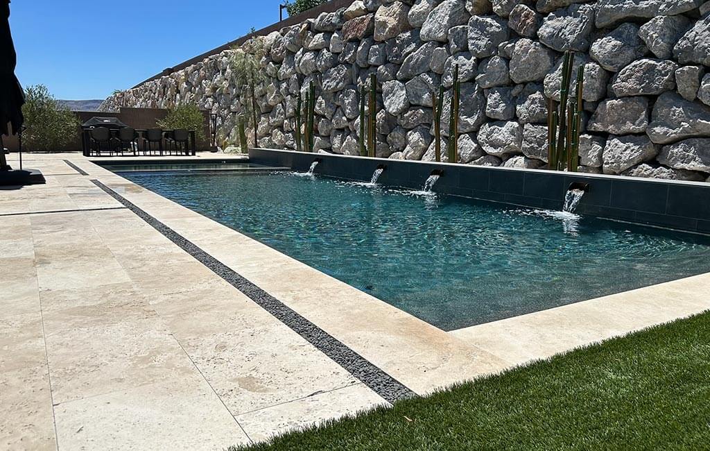 Swimming pool in front of large stone wall